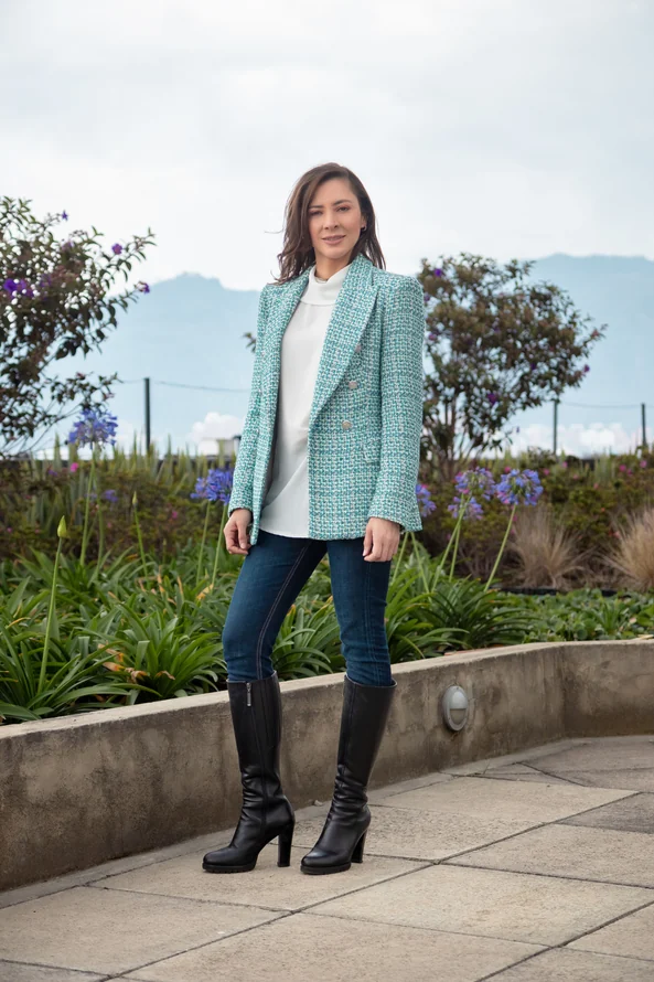 Retrato de cuerpo entero de Alexandra Páramo con chaqueta verde en una terraza