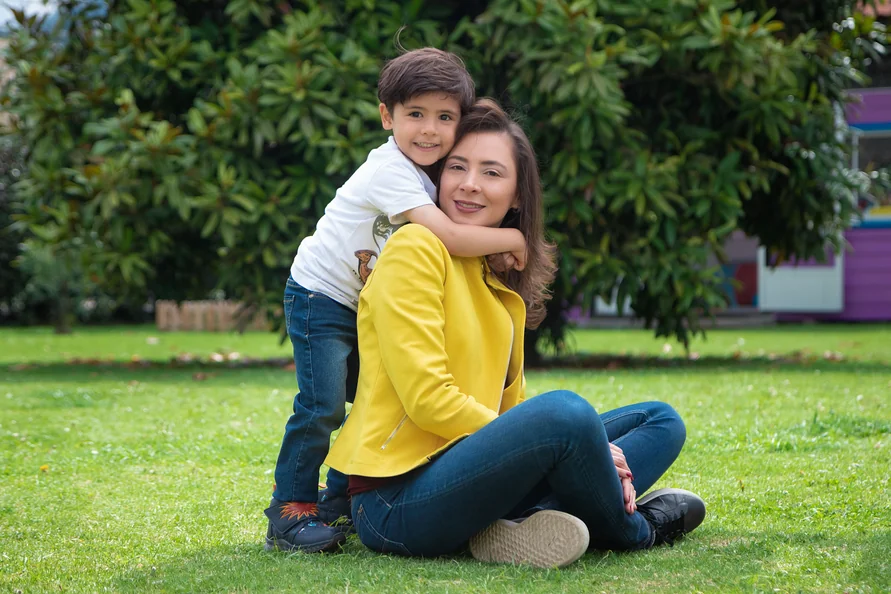 Alexandra Páramo sonríe con un niño abrazado a su espalda en el jardín