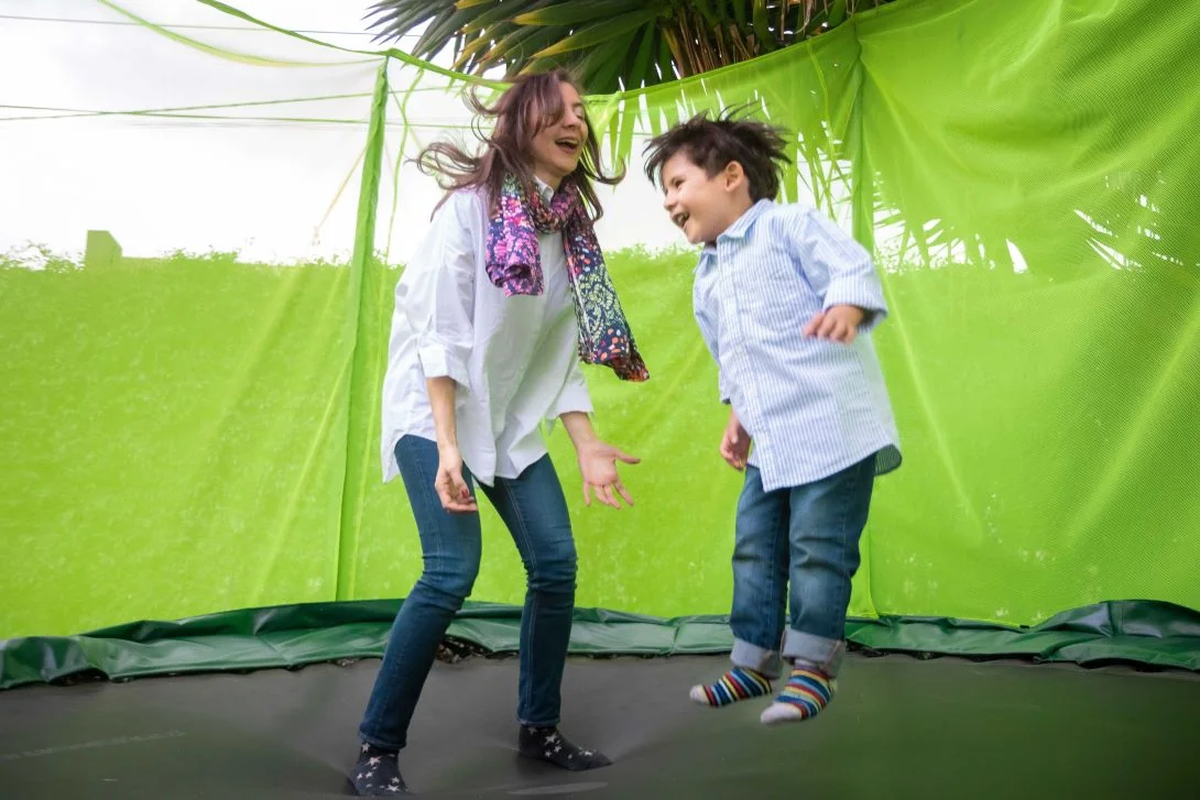 Alexandra Páramo and a young boy jumping on a trampoline