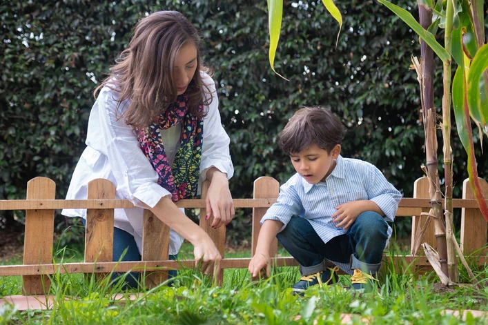 Alexandra Páramo y un niño exploran las plantas junto a una valla de madera