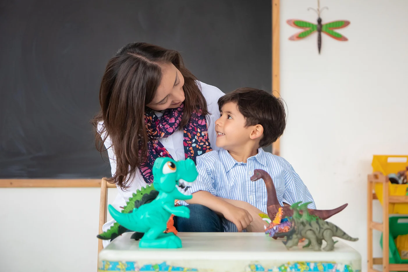 Alexandra Páramo and a child playing with dinosaur figures on a table