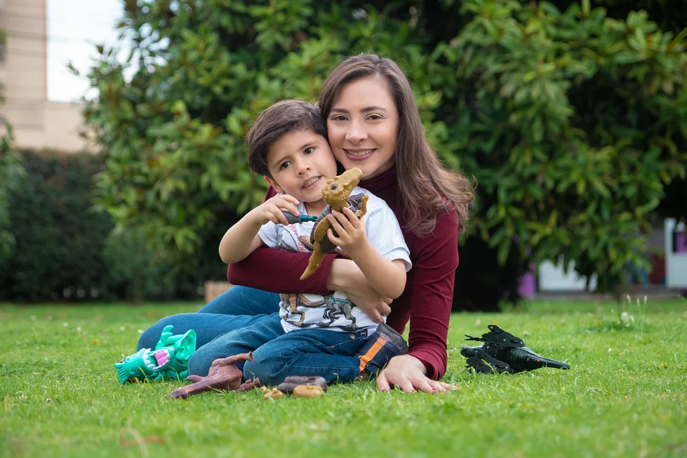 Alexandra Páramo y un niño muestran un dinosaurio de juguete