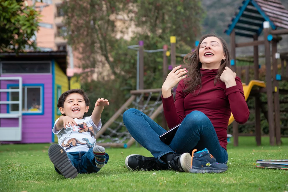 Alexandra Páramo and a child smiling as they play on the grass