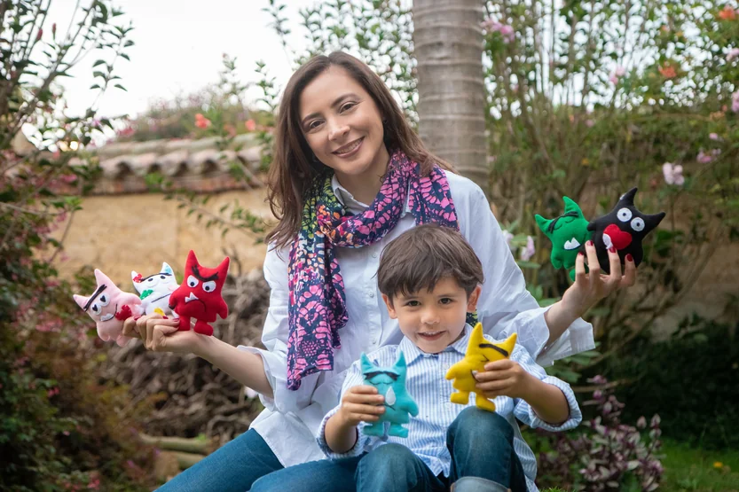 Alexandra Páramo and a child showing colorful figures in the garden
